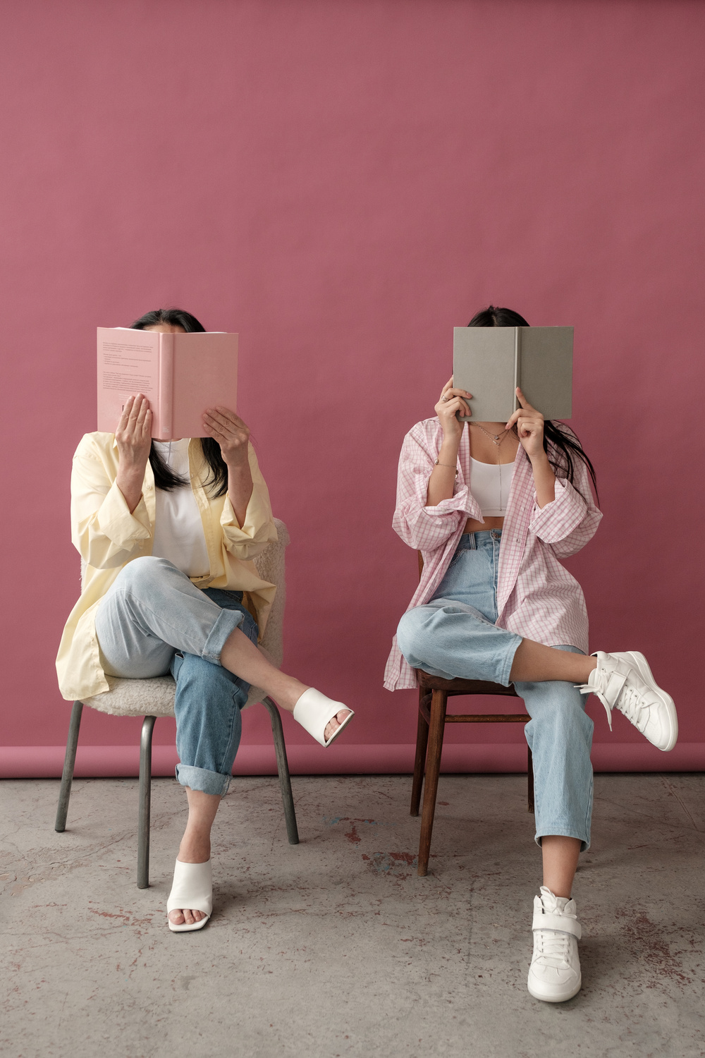 Mom and Daughter Sitting on Chairs Covering Faces with Books